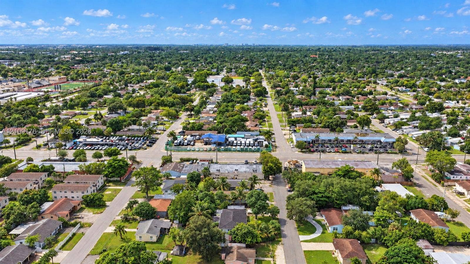 Aerial perspective of a neighborhood featuring an established tree canopy, gridded street layout, and proximity to local commercial infrastructure