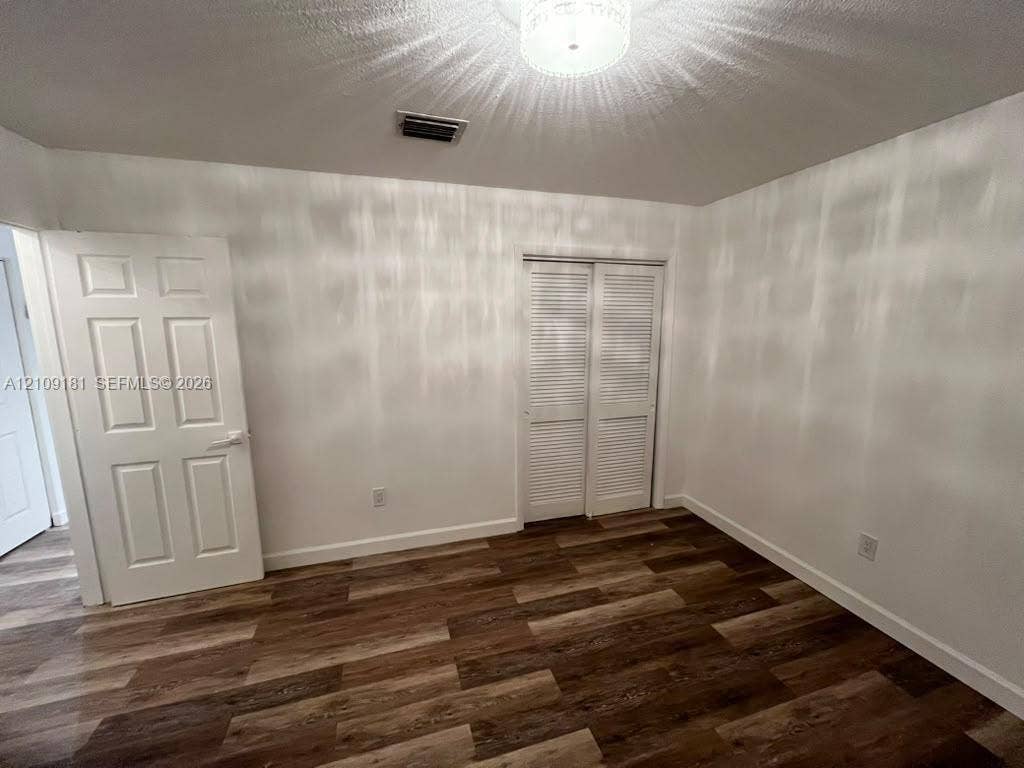 727 SW 10th Street, #1, Hallandale Beach, Hallandale Beach, FL 33009 Interior space featuring wood-finish flooring, a six-panel door, louvered-style closet doors, and a flush-mount ceiling light fixture