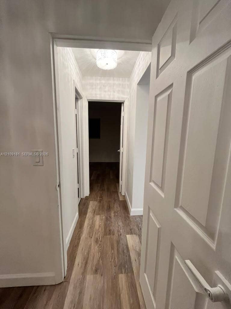 727 SW 10th Street, #1, Hallandale Beach, Hallandale Beach, FL 33009 Hallway featuring wood-finish flooring, white multi-panel doors, and a flush-mount drum ceiling light fixture