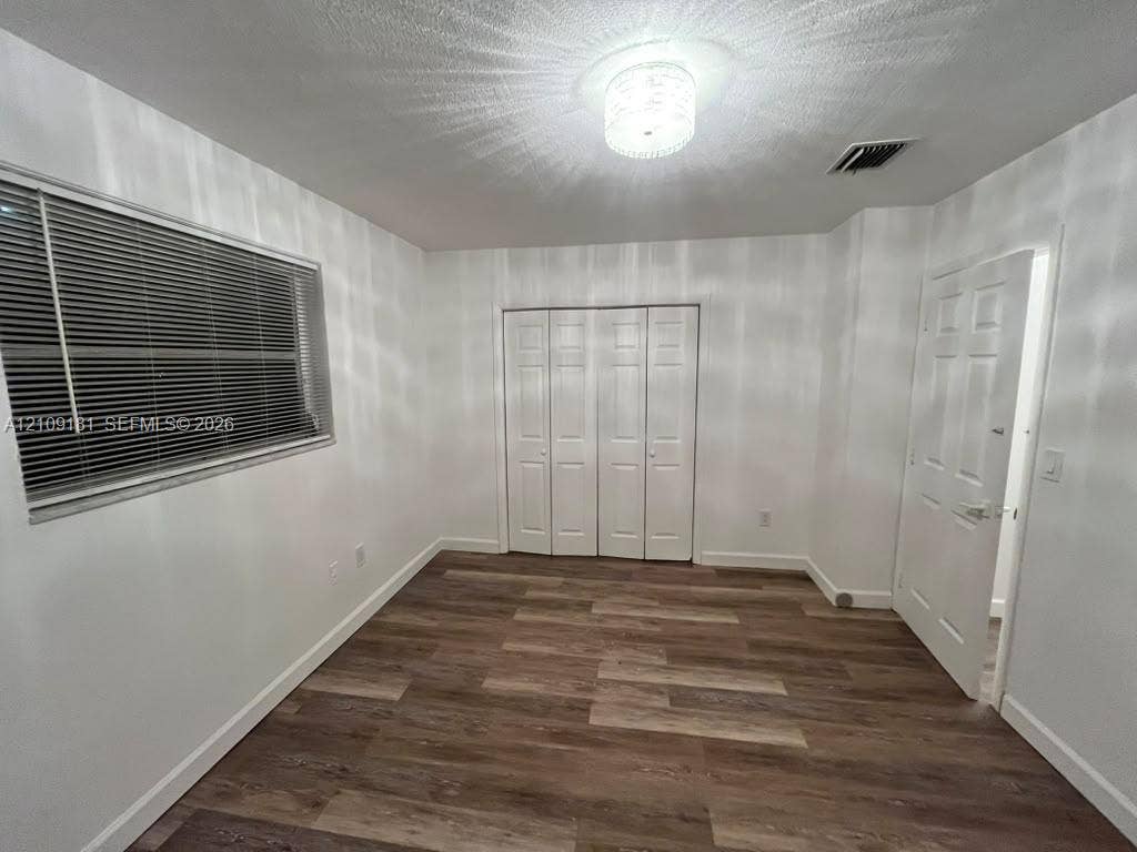 727 SW 10th Street, #1, Hallandale Beach, Hallandale Beach, FL 33009 Room featuring wood-finish flooring, white paneled interior doors, a multi-panel closet, and a decorative flush-mount ceiling light fixture
