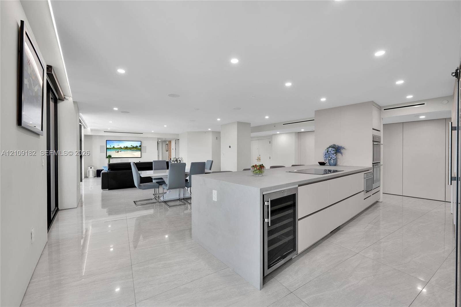 Modern kitchen featuring large format tile flooring, flat-panel cabinetry, a central island with a built-in wine refrigerator, and recessed lighting