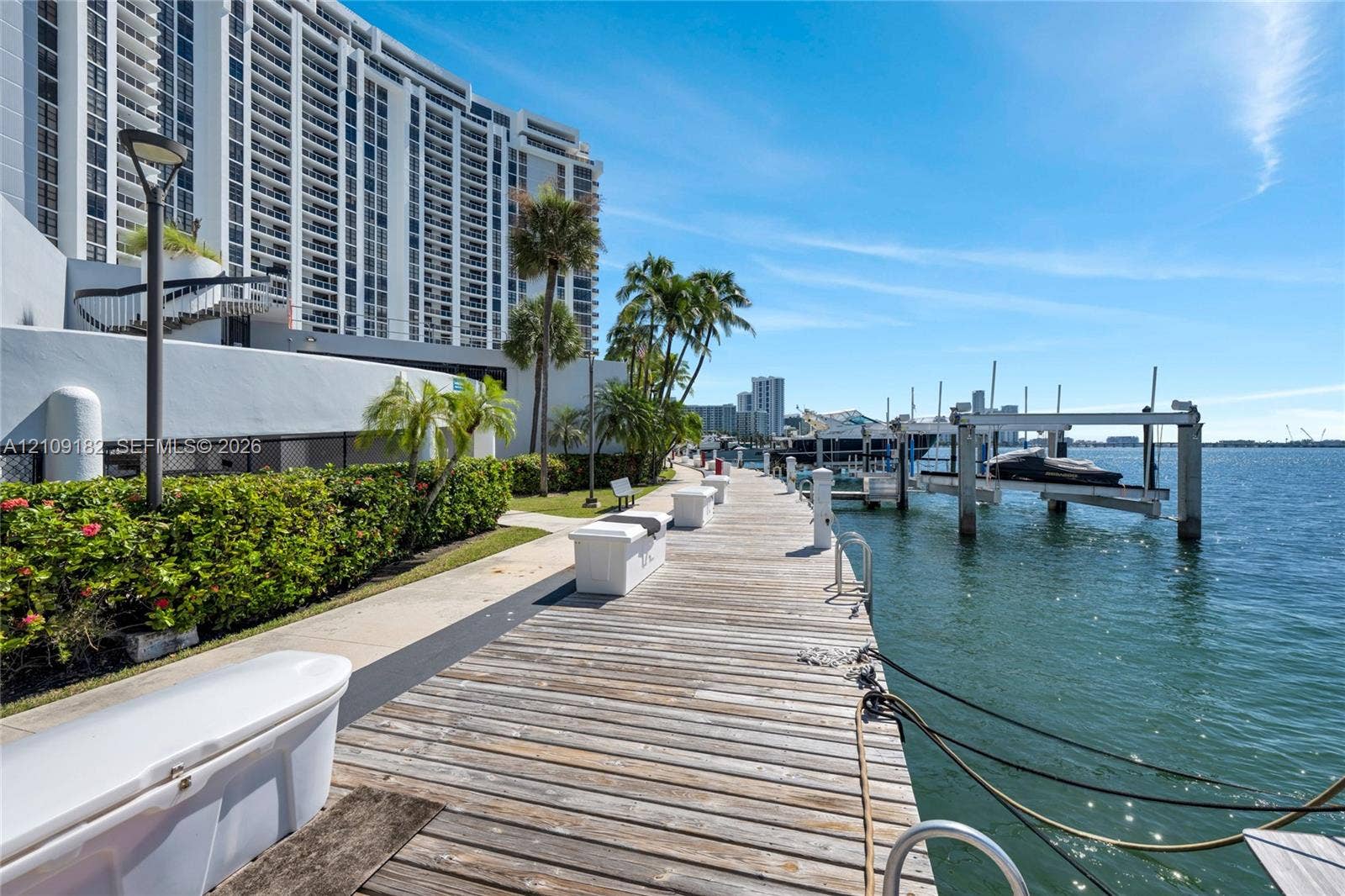 Waterfront wooden boardwalk featuring a private boat slip, integrated dock storage, and native landscaping