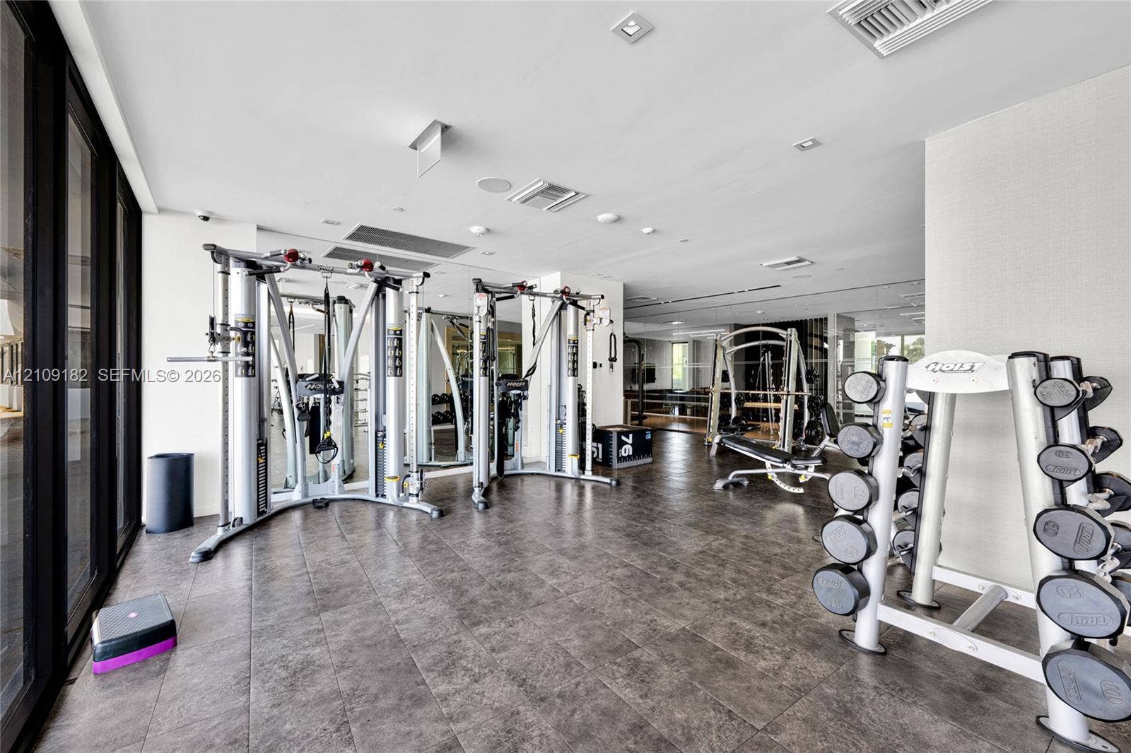 Fitness center featuring large-format tile flooring, recessed ceiling lighting, wall-to-wall mirrors, and floor-to-ceiling windows