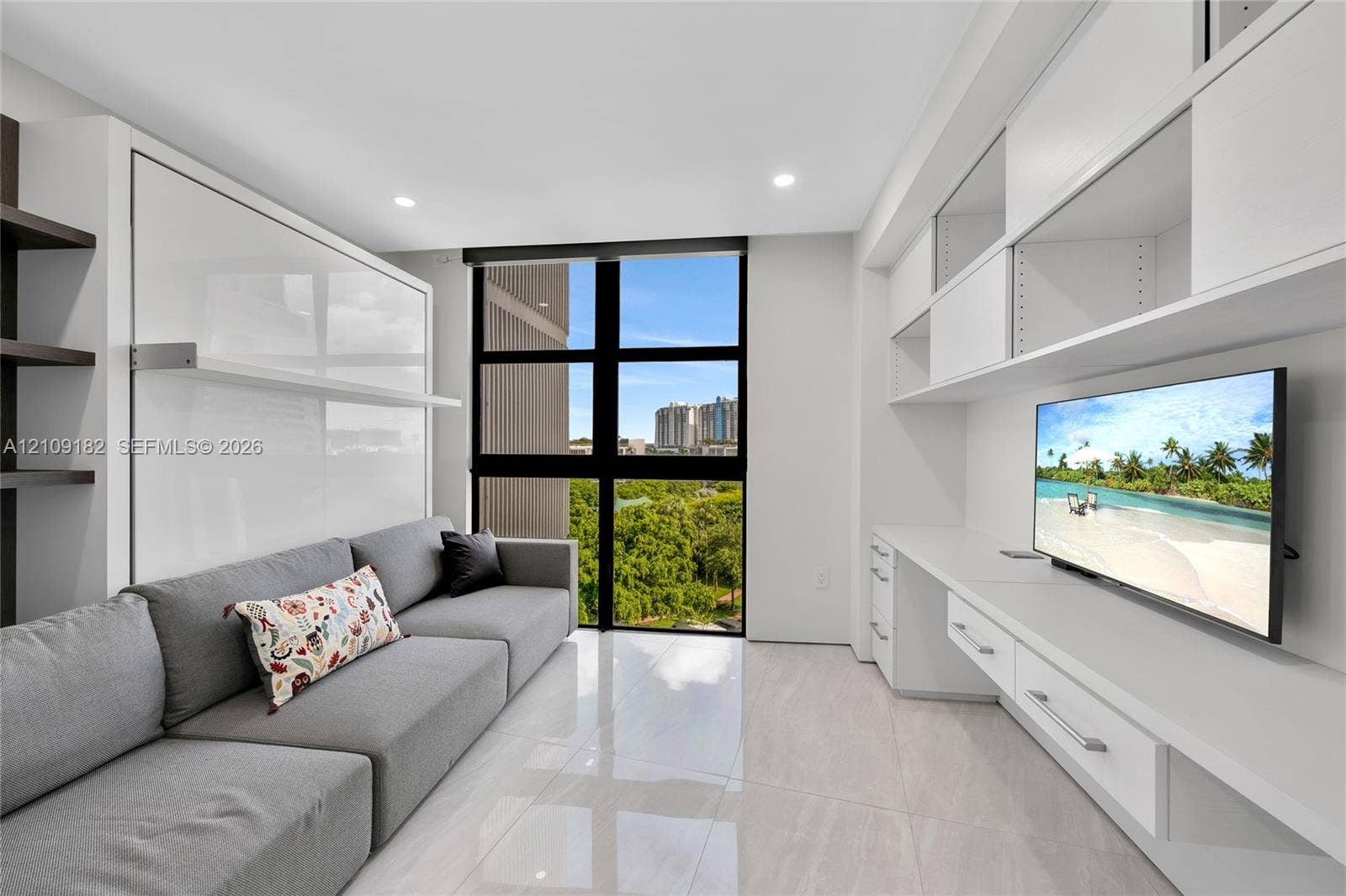 Custom built-in cabinetry featuring high-gloss white finishes, integrated desk workspace, floor-to-ceiling multi-pane window, and light-toned tile flooring