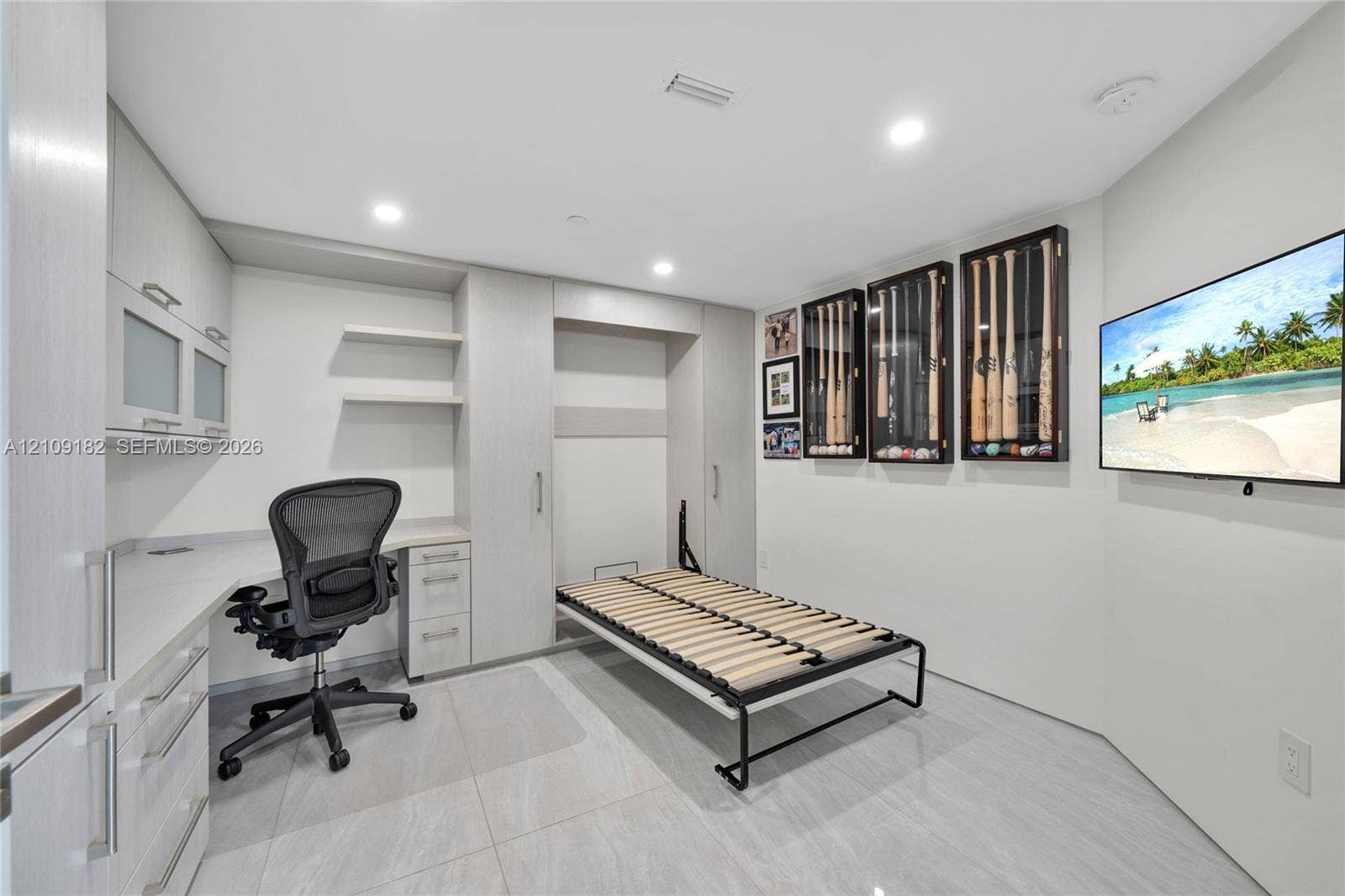 Built-in light-tone cabinetry with integrated workspace, recessed lighting, and large-format tile flooring