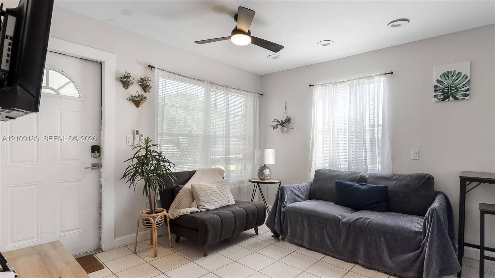 1009 NE 17th Court, Fort Lauderdale, FL 33305 Neutral-toned interior featuring ceramic tile flooring, recessed lighting, a modern ceiling fan with integrated light, and large windows with natural light exposure