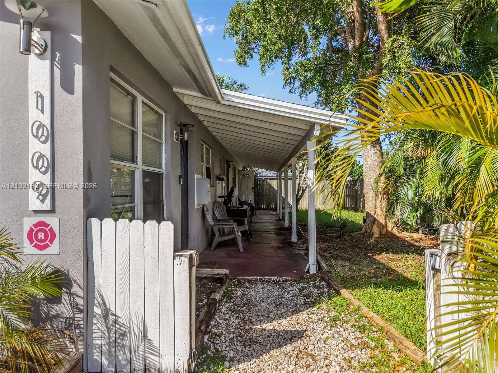 1009 NE 17th Court, Fort Lauderdale, FL 33305 Covered exterior walkway with supporting columns, gravel pathway, and white picket fencing