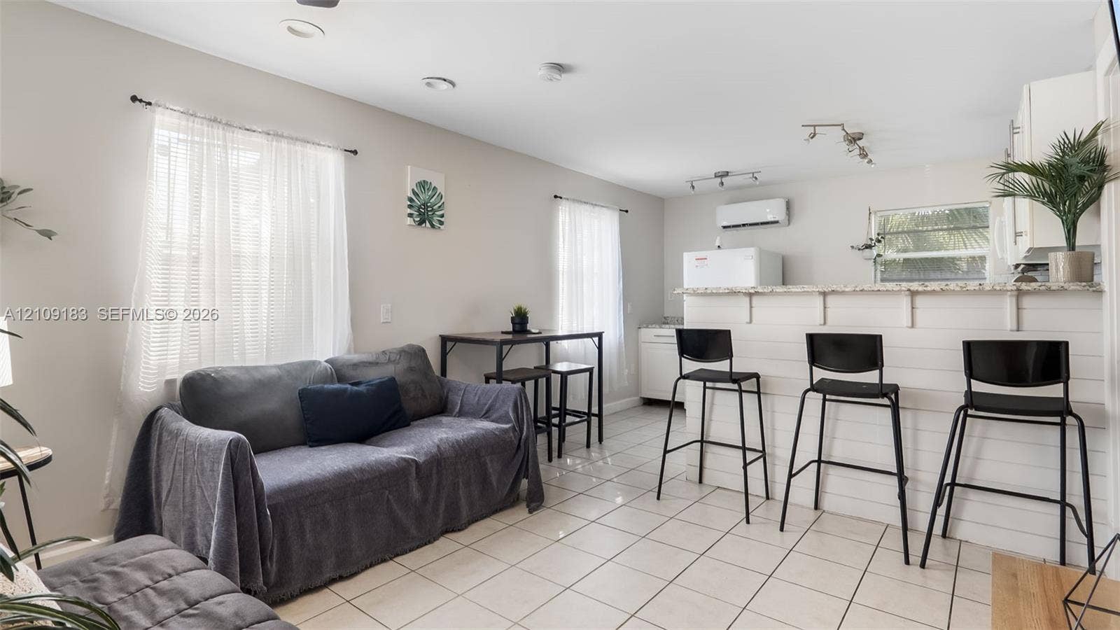 1009 NE 17th Court, Fort Lauderdale, FL 33305 Neutral-toned interior featuring ceramic tile flooring, recessed lighting, and a breakfast bar with white horizontal paneling and a stone-surface countertop
