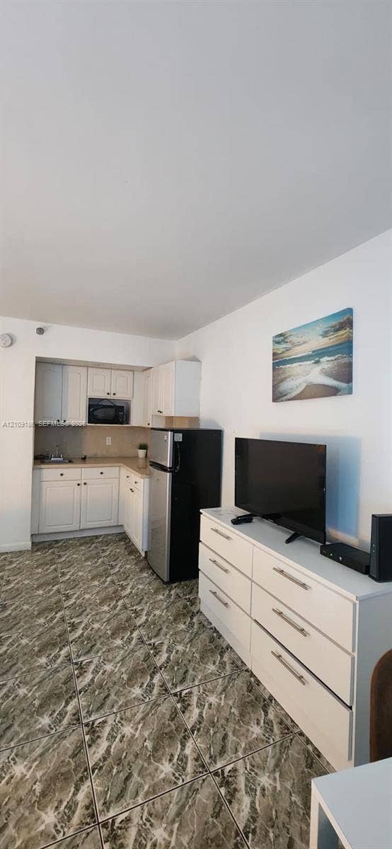 Kitchen area featuring white cabinetry, a built-in microwave, and stone-patterned tile flooring