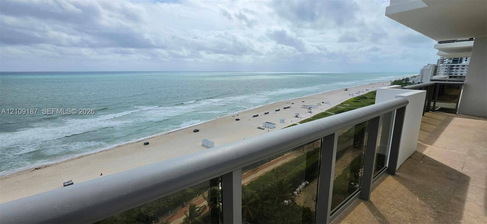 6039 Collins Avenue, #1625, Miami Beach, FL 33140 Private balcony with marble flooring and a glass-paneled railing overlooking the coastline and direct front 180 ocean view.