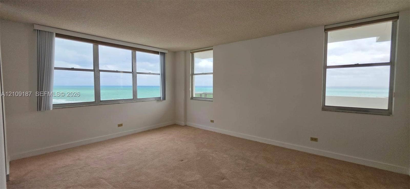6039 Collins Avenue, #1625, Miami Beach, FL 33140 Floor-to-ceiling glass sliding doors to balcony and direct front ocean view, wall-to-wall carpeting, and a custom vertical wood-slat accent wall
