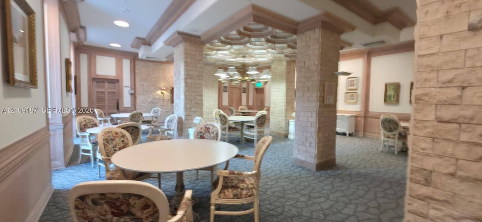 6039 Collins Avenue, #1625, Miami Beach, FL 33140 Women's playroom featuring ornate tiered tray ceilings, decorative masonry pillars, layered crown molding, and recessed lighting.