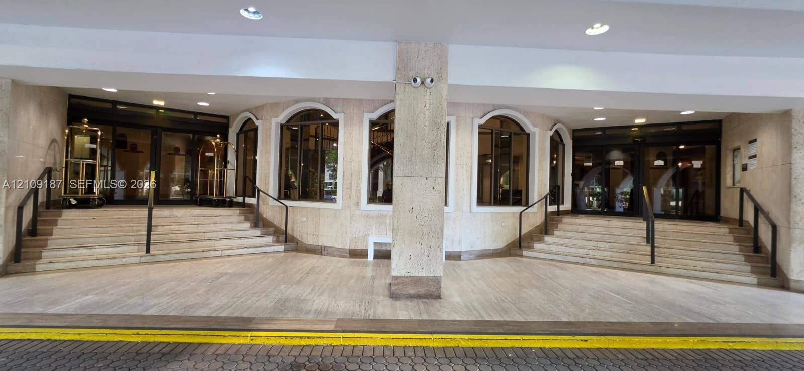 6039 Collins Avenue, #1625, Miami Beach, FL 33140 Building covered main entrance and valet parking, featuring marble facade, arched windows, dual staircases with metal handrails, and multi-pane glass entry doors