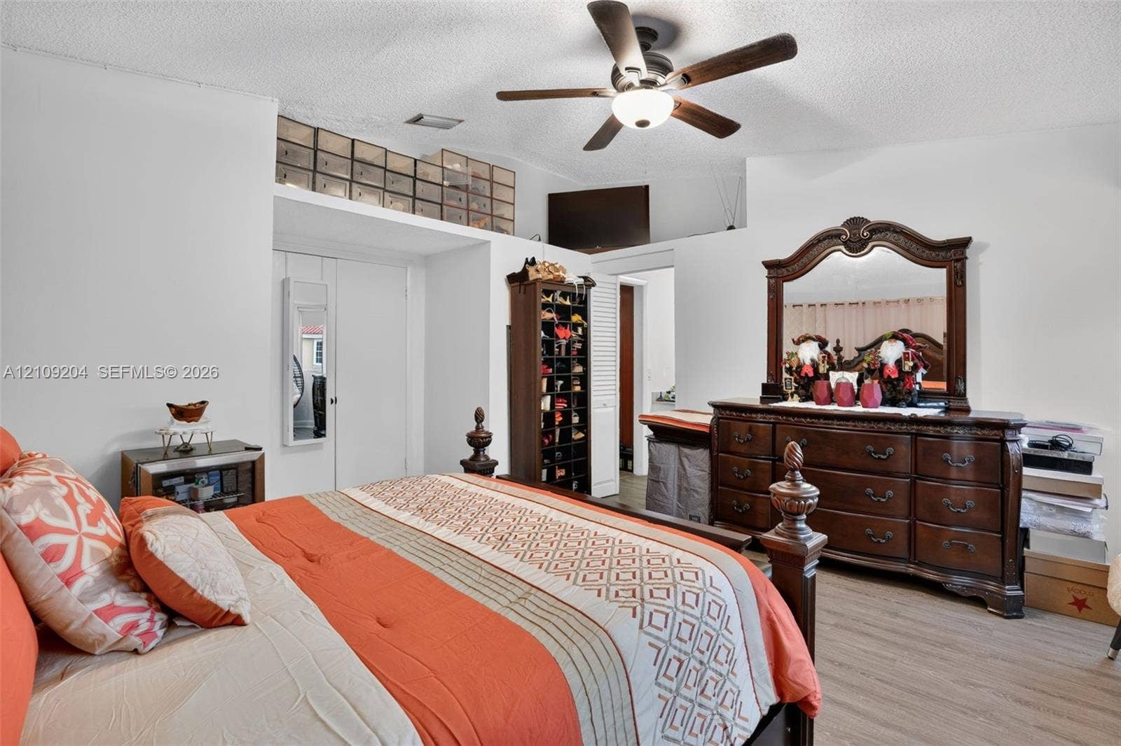 Bedroom featuring wood-finish flooring, a ceiling fan with integrated lighting, and built-in closet storage with overhead shelving