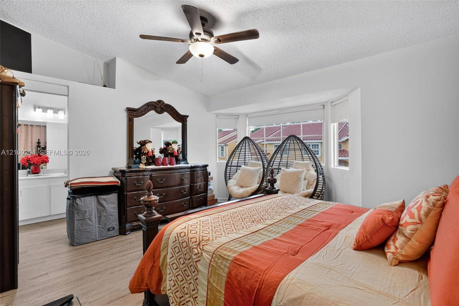 Vaulted ceiling featuring a central five-blade ceiling fan, expansive bay window, and light-toned wood-finish flooring