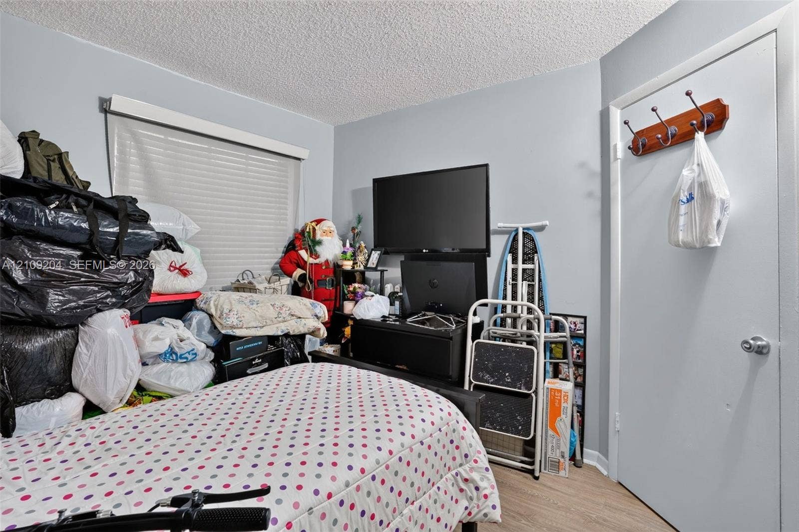 Room featuring wood-finish flooring, a neutral wall finish, and a window with fitted blinds