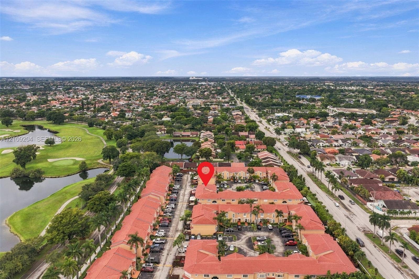 Aerial perspective of a multi-unit complex featuring terra-cotta tile roofing and paved surface parking
