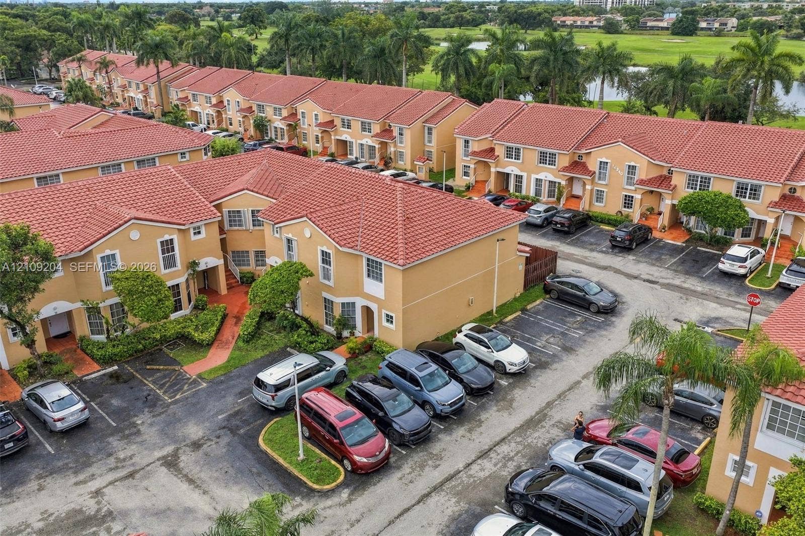 Multi-story townhome community featuring Mediterranean-style architecture, red tile roofing, stucco exterior facades, and designated surface parking