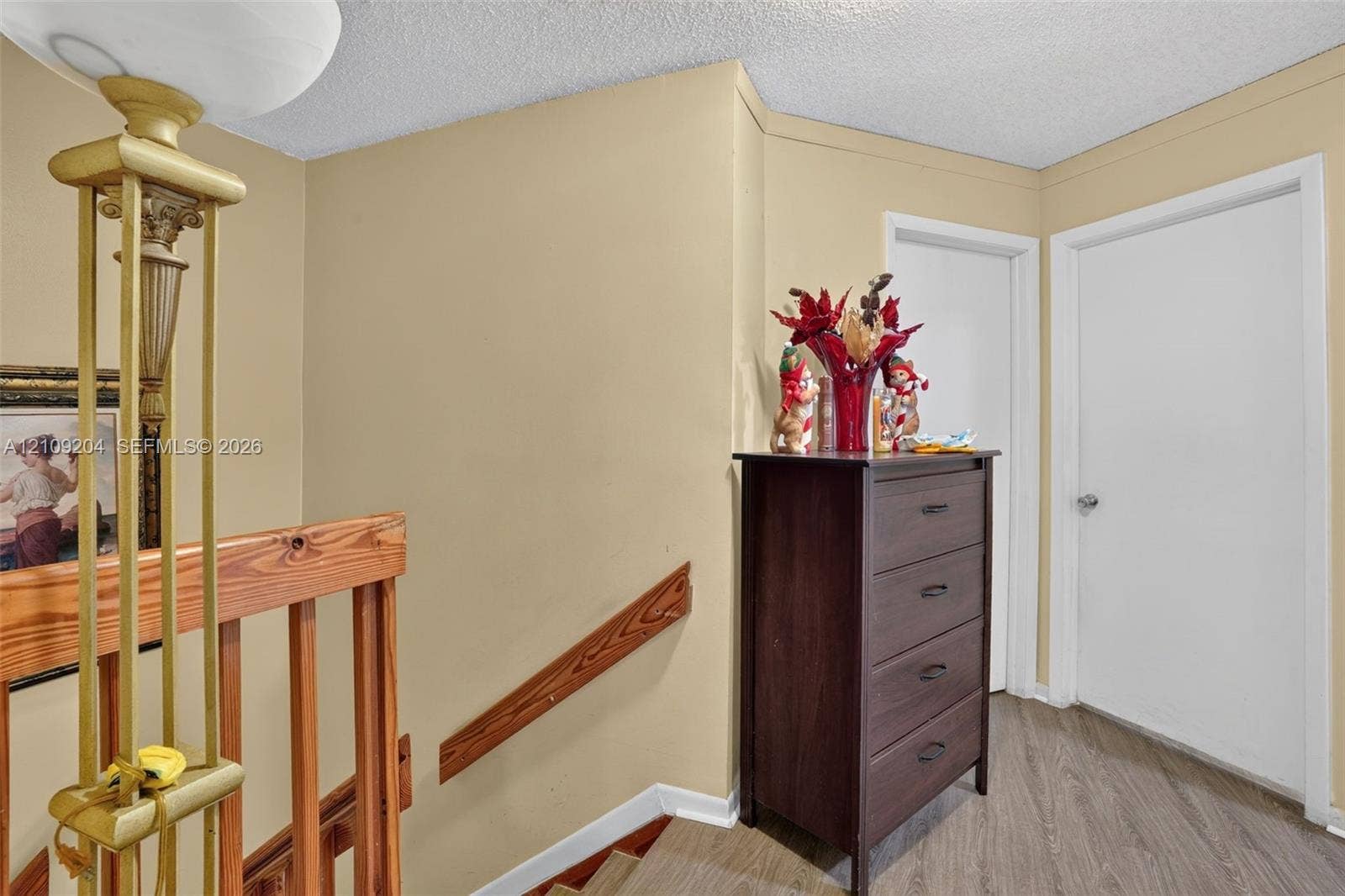 Wood-finish flooring, natural wood handrail, and white panel doors