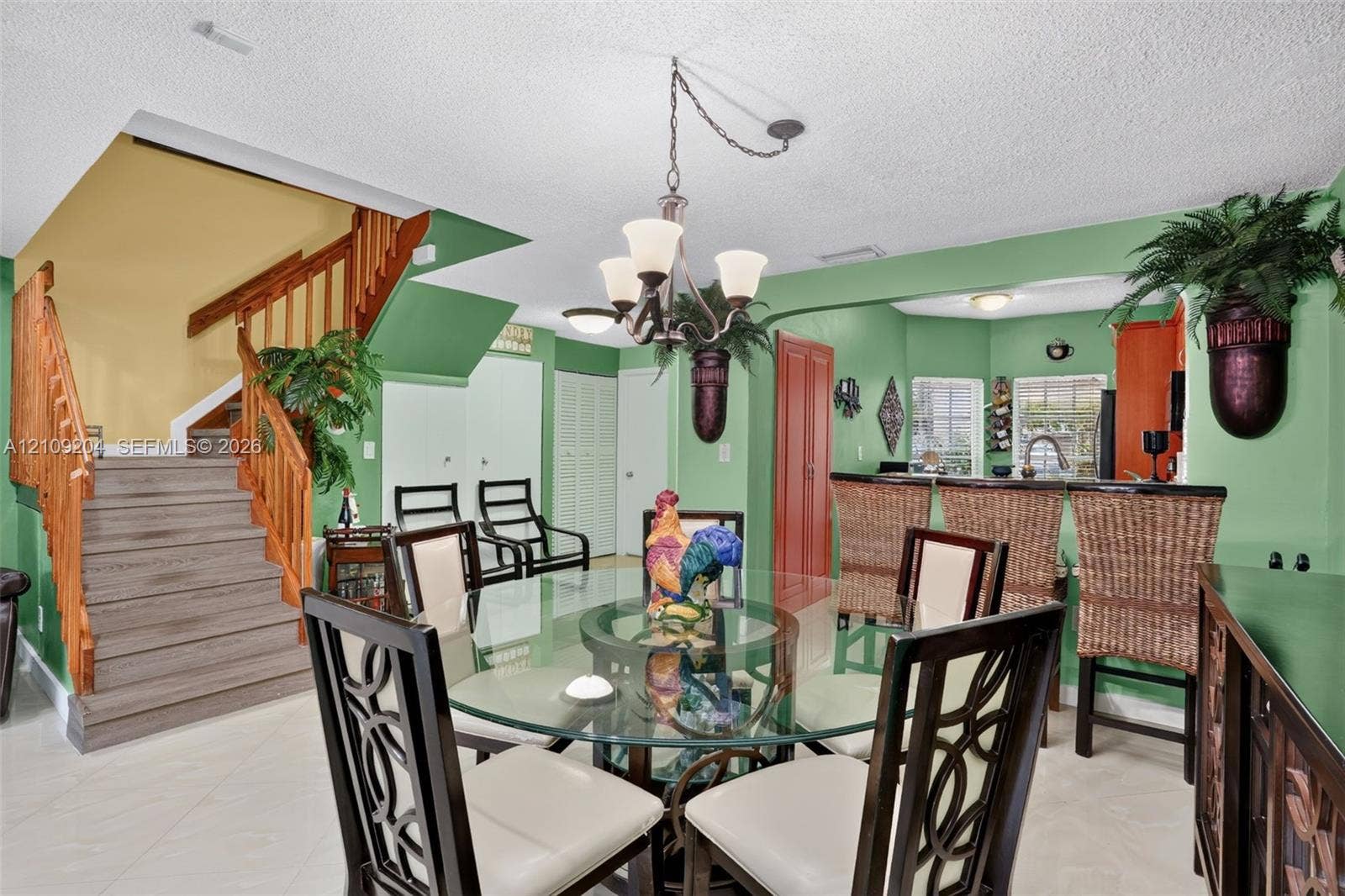 Interior featuring tile flooring, a tiered wooden staircase with matching handrails, and a multi-light metal chandelier