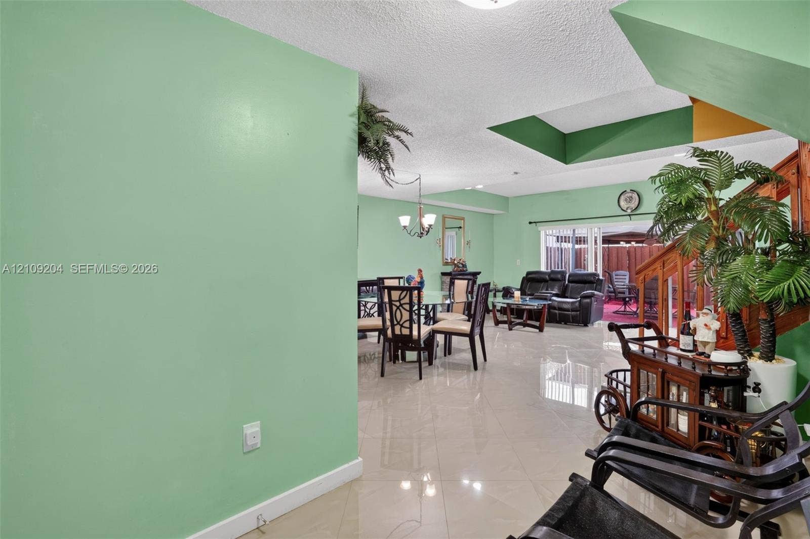 Large-format tile flooring, recessed ceiling alcove, and sliding glass doors with direct exterior access