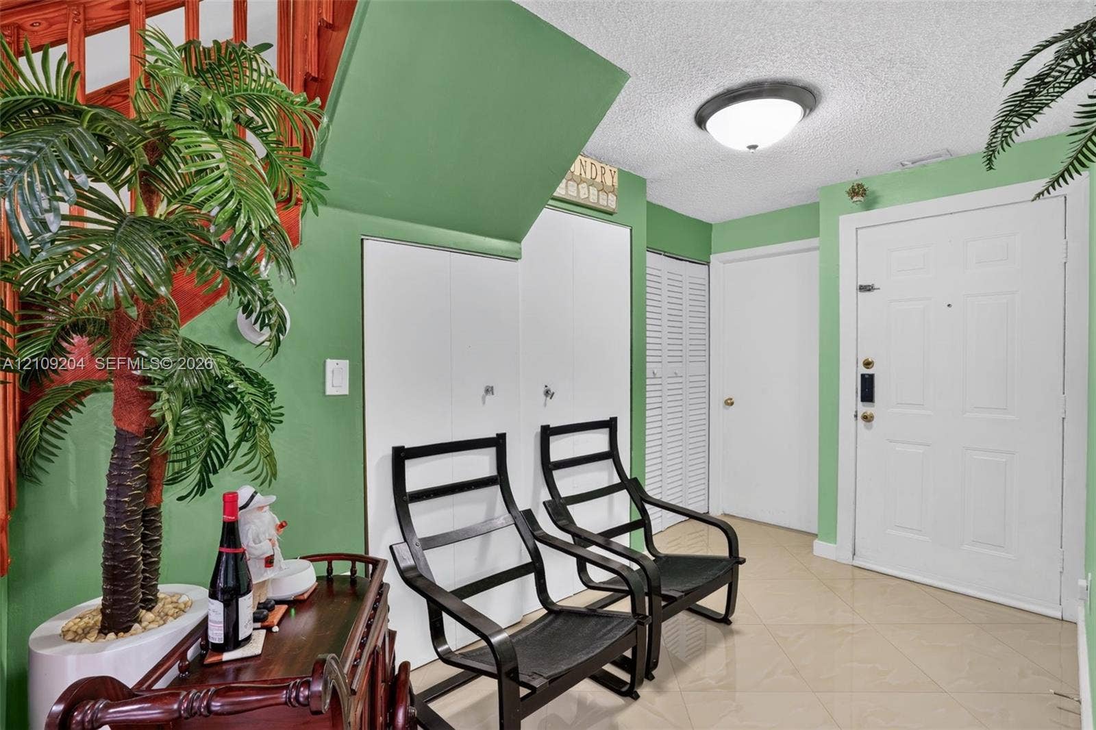 Entryway featuring tiled flooring, flush-mount ceiling lighting, white paneled doors, and louvered closet doors