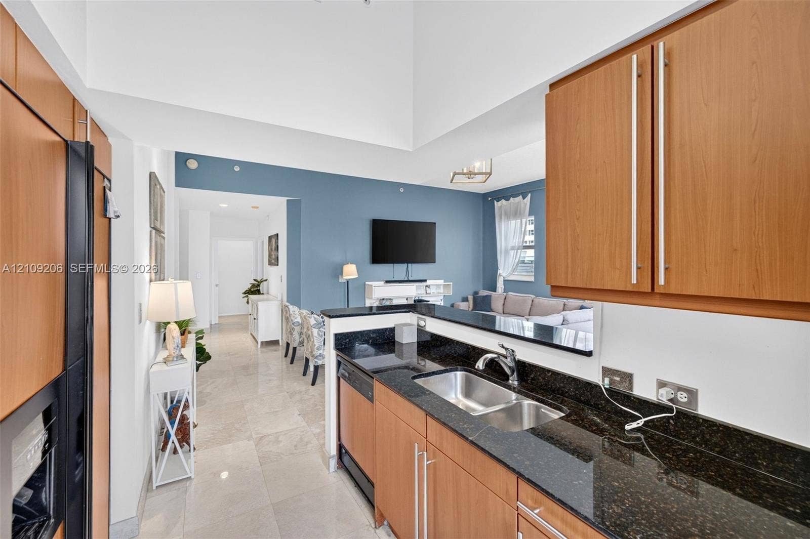 2080 S Ocean Drive, #112, Hallandale Beach, Hallandale Beach, FL 33009 Kitchen featuring wood-finish cabinetry, dark stone countertops, stainless steel dual-basin sink, and tile flooring, set under a vaulted ceiling