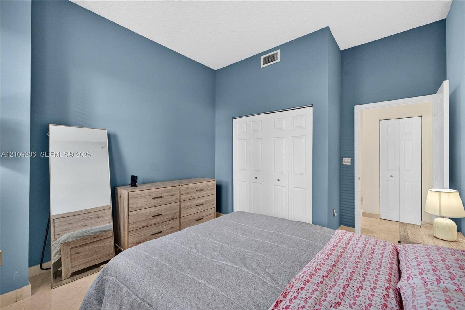 2080 S Ocean Drive, #112, Hallandale Beach, Hallandale Beach, FL 33009 High-ceiling room featuring blue-painted walls, tile flooring, and two white bi-fold closet doors