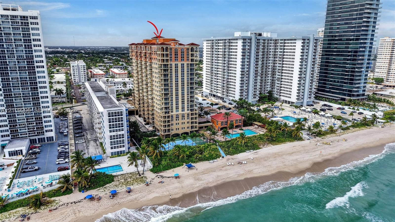 2080 S Ocean Drive, #112, Hallandale Beach, Hallandale Beach, FL 33009 High-rise residential building featuring stucco exterior, arched window detailing, terracotta tile roofing, and direct beach access