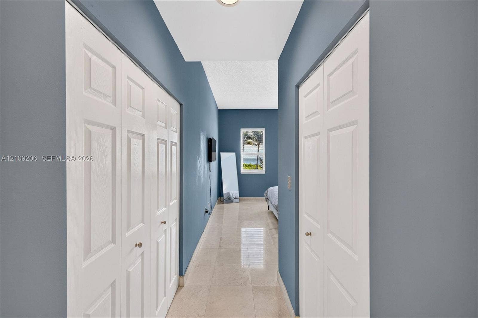 2080 S Ocean Drive, #112, Hallandale Beach, Hallandale Beach, FL 33009 Hallway featuring polished tile flooring, dual six-panel bifold closet doors, and a single window with exterior scenery