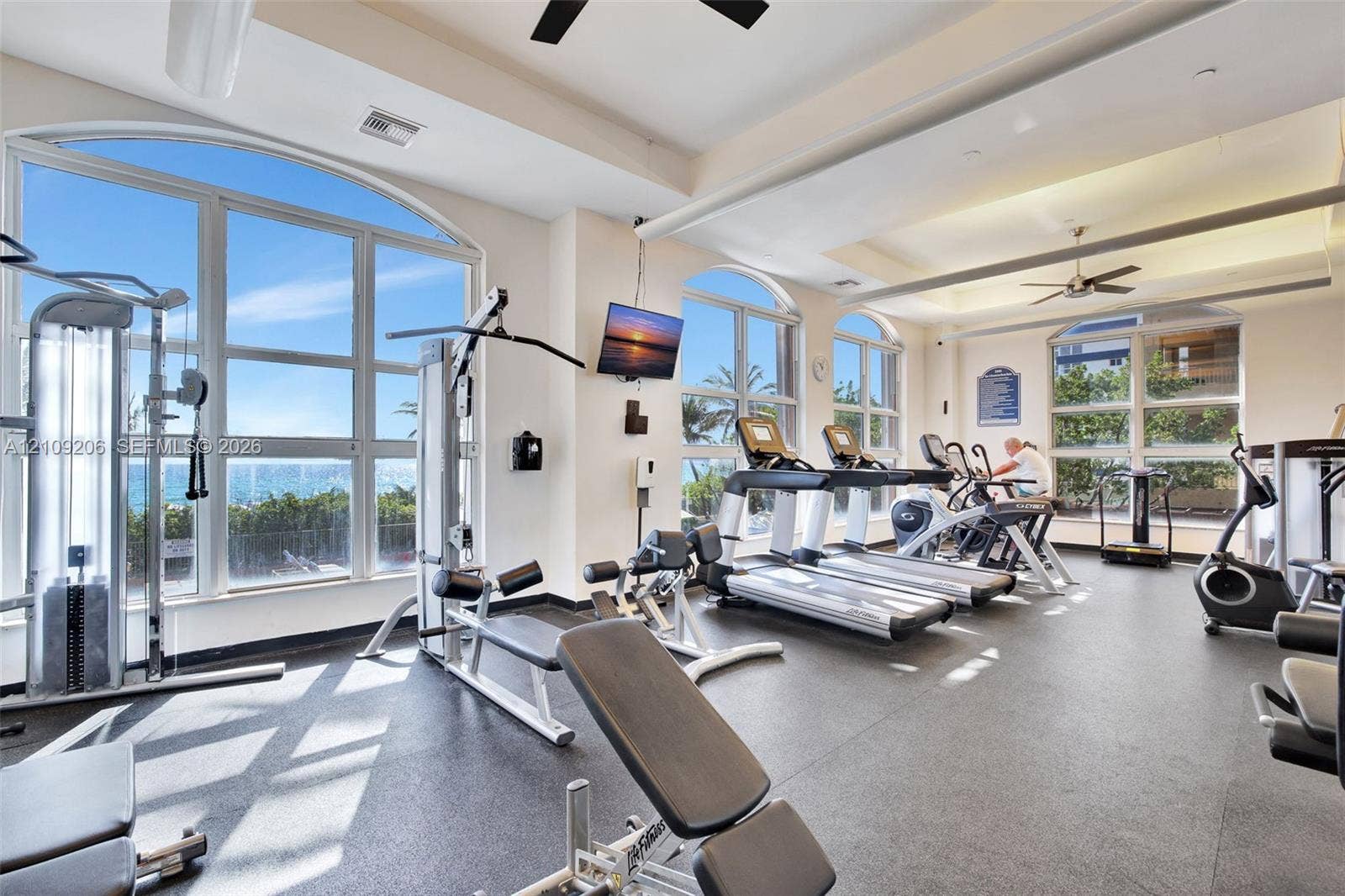 2080 S Ocean Drive, #112, Hallandale Beach, Hallandale Beach, FL 33009 Fitness center featuring arched floor-to-ceiling windows, high tray ceilings, recessed lighting, and durable rubber flooring
