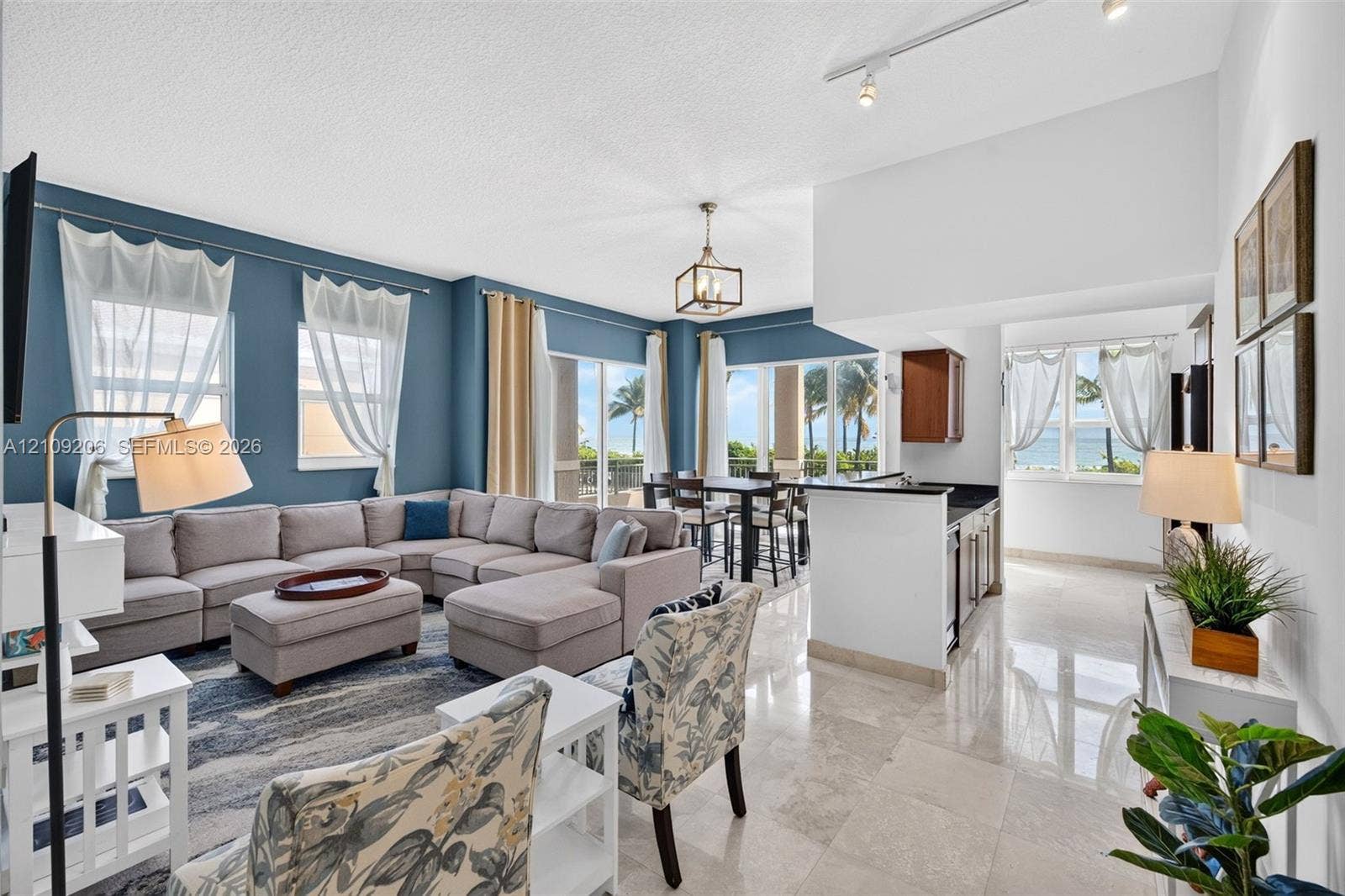 2080 S Ocean Drive, #112, Hallandale Beach, Hallandale Beach, FL 33009 Open-concept interior featuring light-toned stone tile flooring, high ceilings with track and pendant lighting, and floor-to-ceiling glass sliding doors