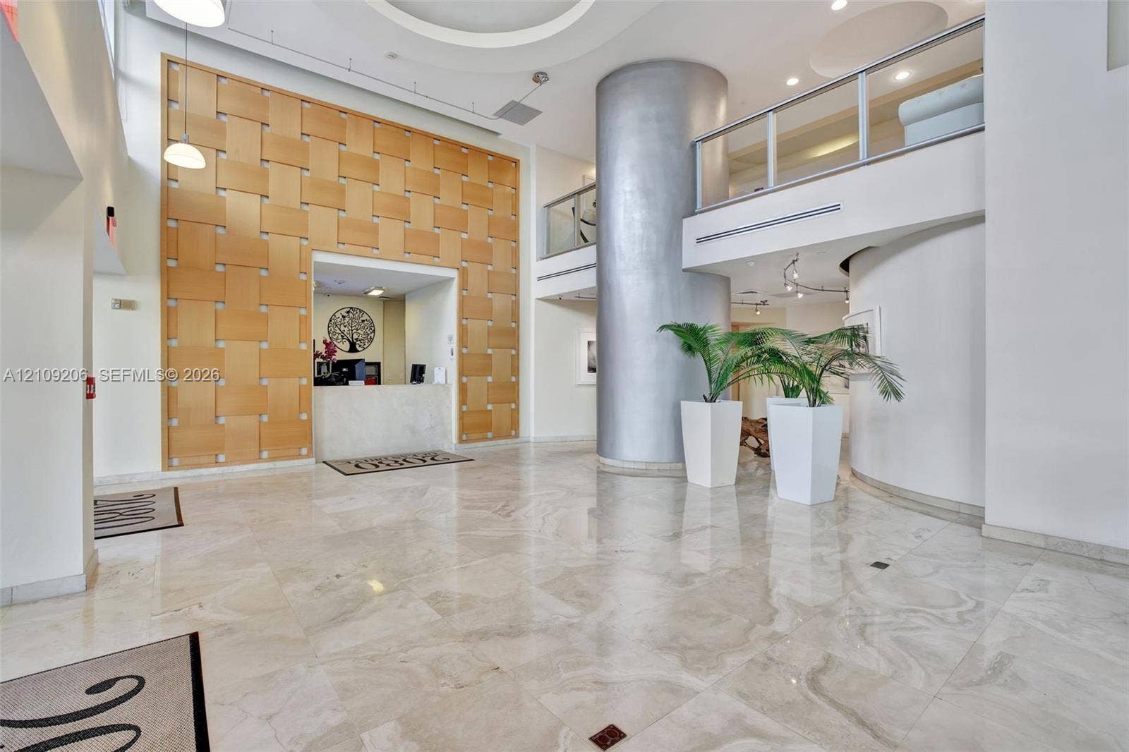 2080 S Ocean Drive, #112, Hallandale Beach, Hallandale Beach, FL 33009 Grand entrance featuring polished stone flooring, a woven-wood accent wall, a cylindrical architectural column, and a mezzanine with glass-panel railings