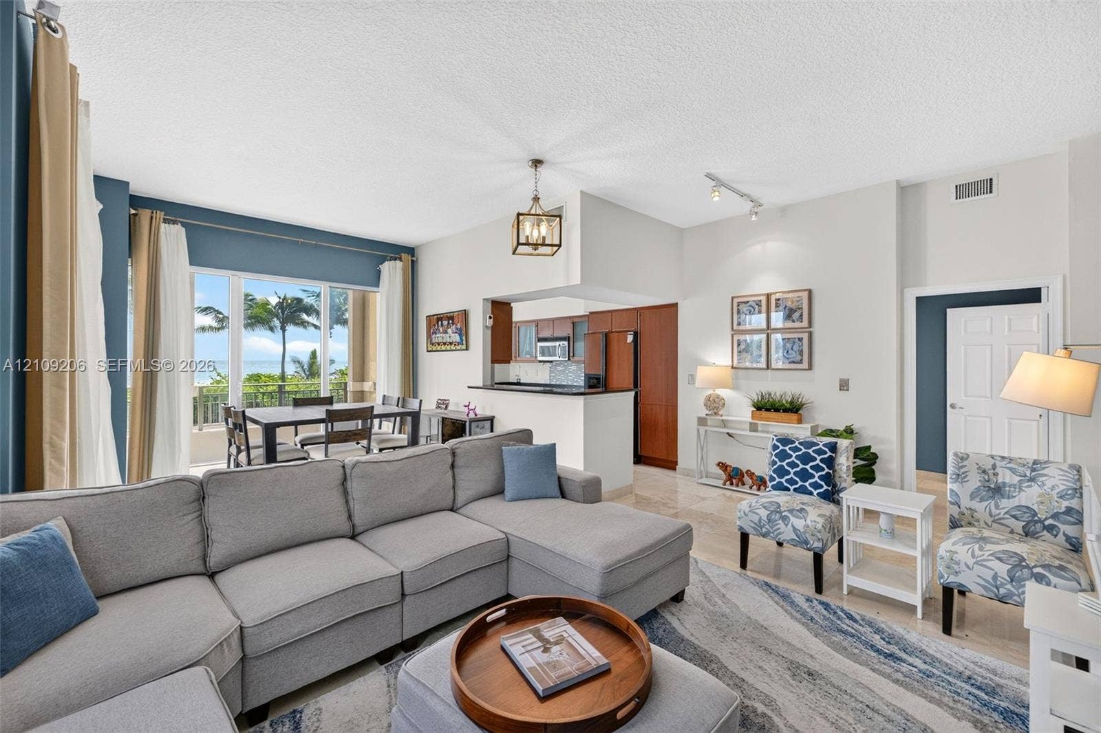 2080 S Ocean Drive, #112, Hallandale Beach, Hallandale Beach, FL 33009 Open-concept interior featuring large windows with coastal scenery, wood cabinetry, polished stone flooring, and a decorative lantern pendant light