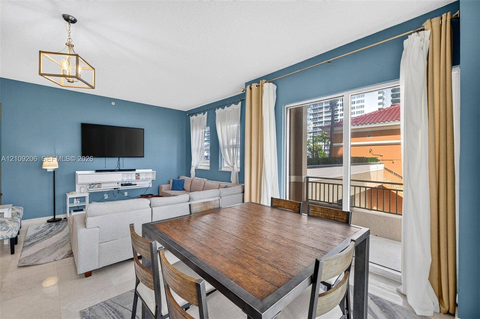 2080 S Ocean Drive, #112, Hallandale Beach, Hallandale Beach, FL 33009 Large-format sliding glass doors, geometric metal-frame chandelier, expansive tile flooring, and private balcony with metal railing