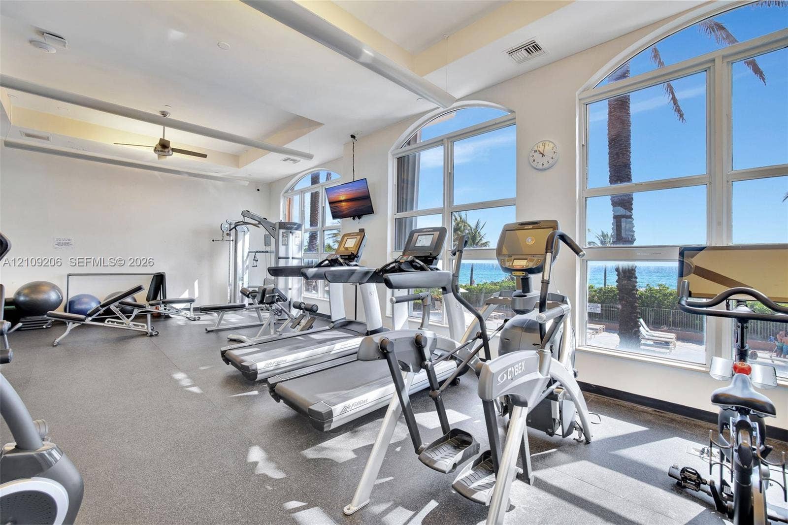 2080 S Ocean Drive, #112, Hallandale Beach, Hallandale Beach, FL 33009 Fitness center featuring high ceilings, rubberized flooring, ceiling fan, and arched floor-to-ceiling windows with coastal scenery