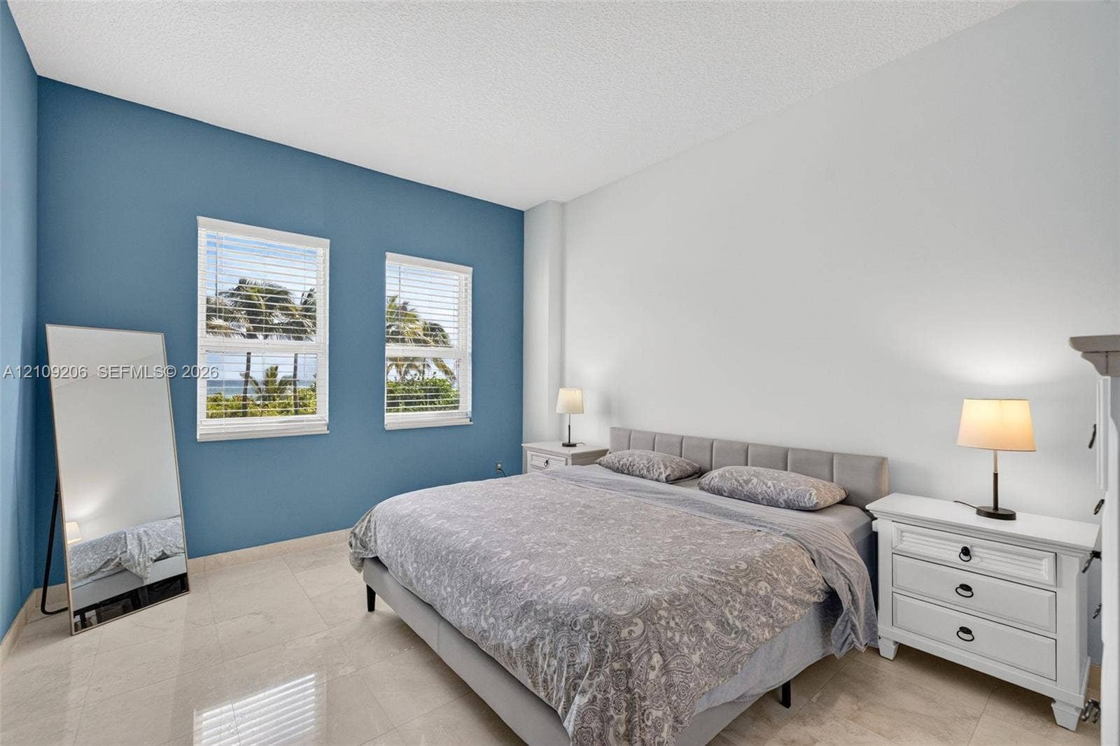 2080 S Ocean Drive, #112, Hallandale Beach, Hallandale Beach, FL 33009 Bedroom featuring two dual-pane windows with integrated blinds, accent-painted wall, and large-format tile flooring