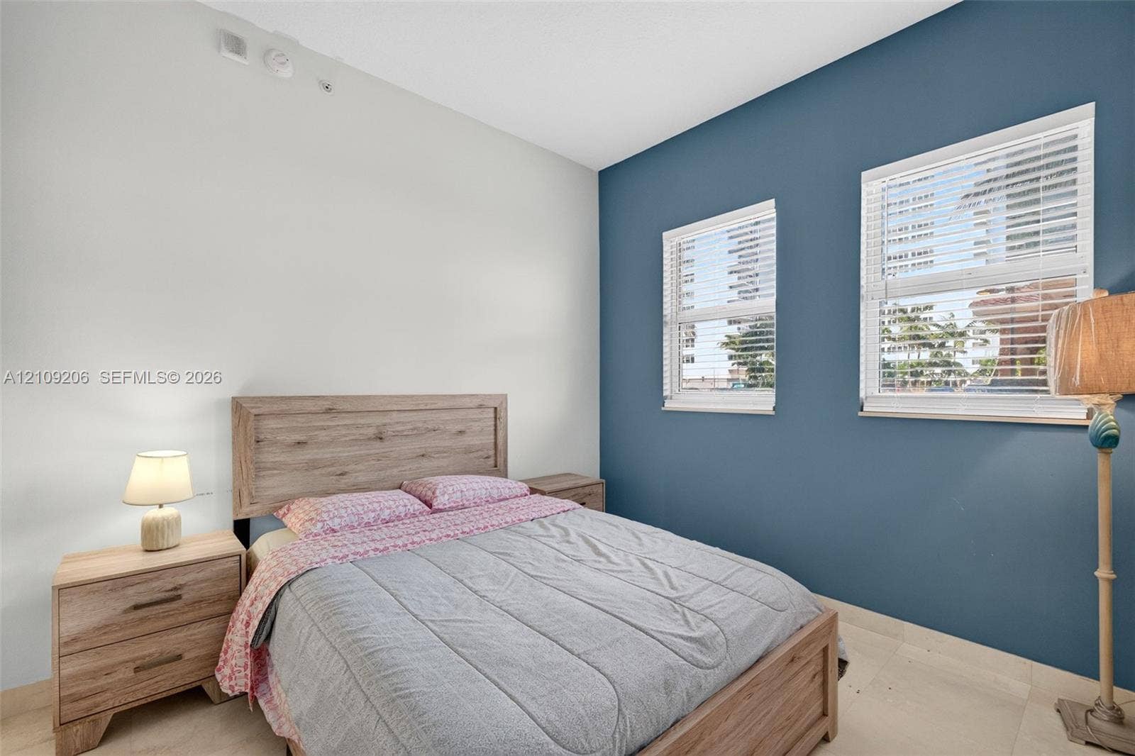 2080 S Ocean Drive, #112, Hallandale Beach, Hallandale Beach, FL 33009 Room featuring a deep blue accent wall, neutral wall tones, two windows with horizontal blinds, and smooth-finish flooring
