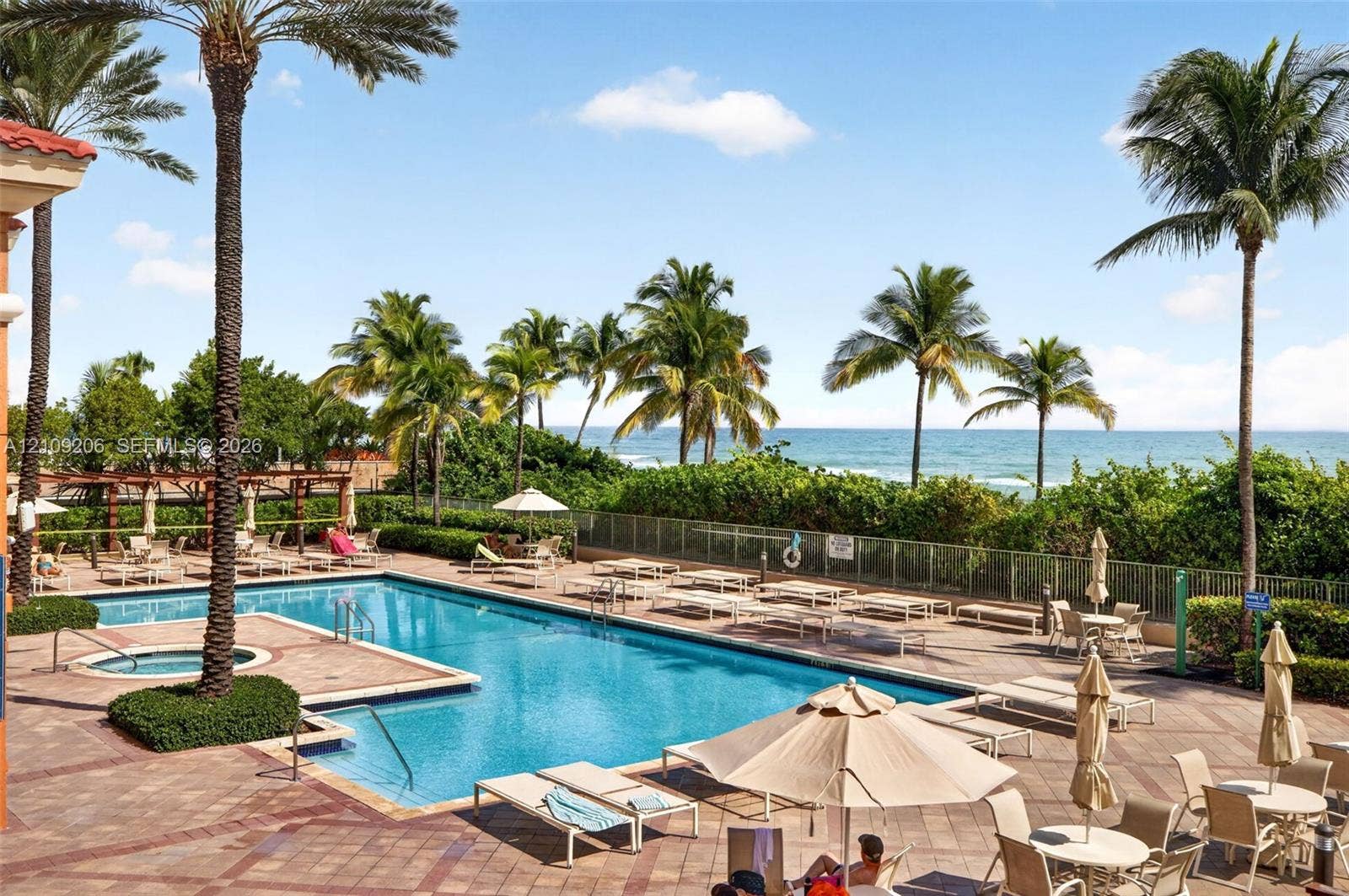 2080 S Ocean Drive, #112, Hallandale Beach, Hallandale Beach, FL 33009 Swimming pool and integrated spa featuring a brick-paver deck and mature palm tree landscaping