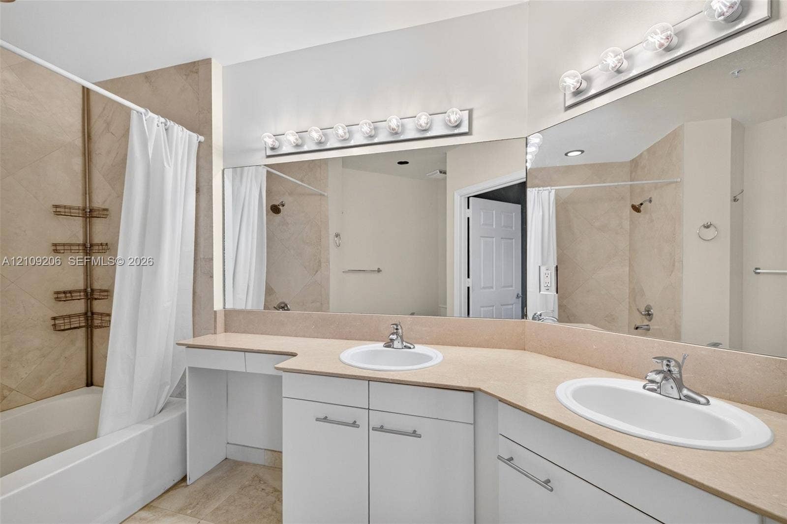 2080 S Ocean Drive, #112, Hallandale Beach, Hallandale Beach, FL 33009 Bathroom featuring a dual-sink vanity with neutral-toned countertops, a large wall-to-wall mirror, built-in cabinetry, and a tub-shower combination with tiled surround