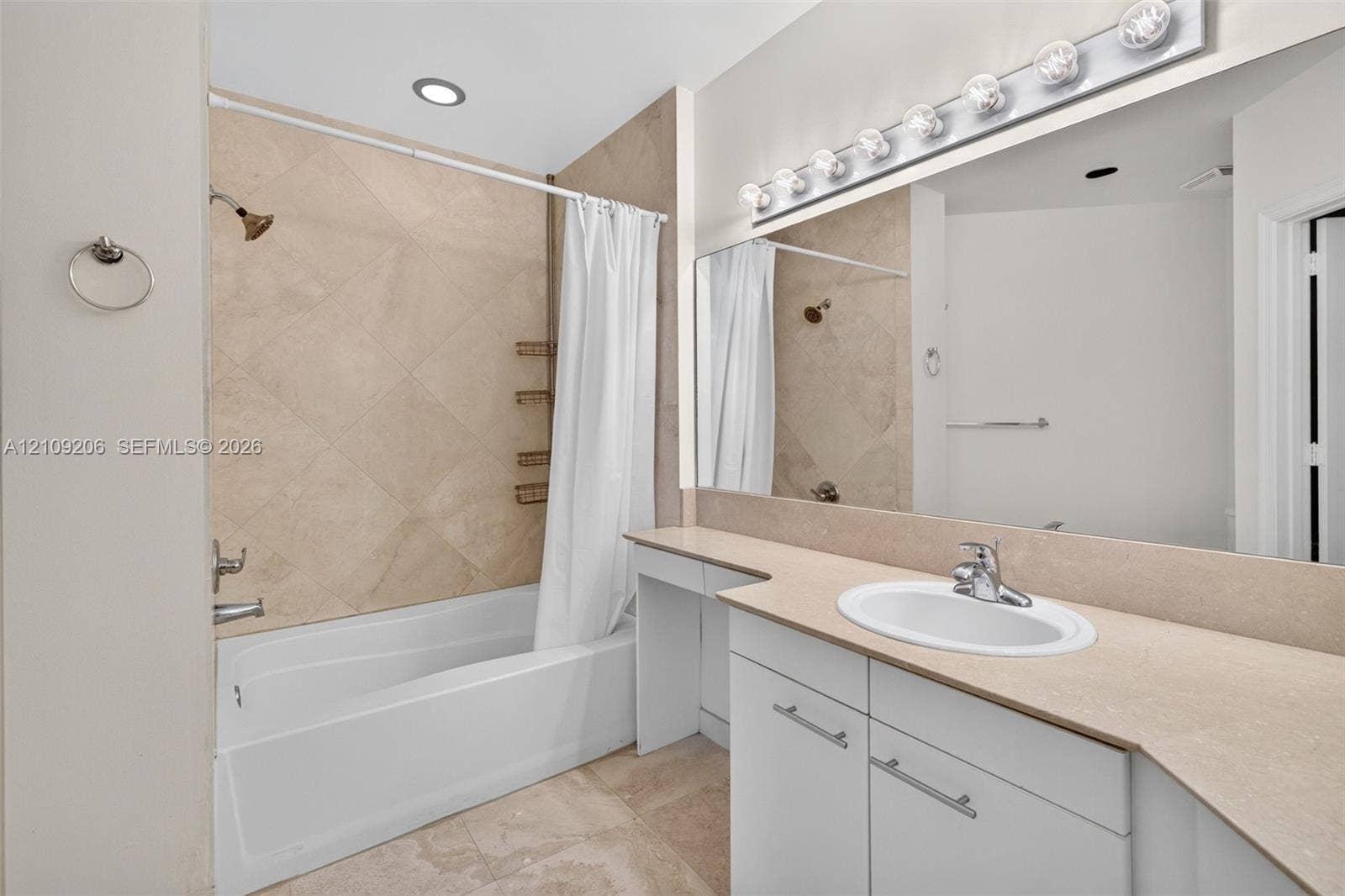 2080 S Ocean Drive, #112, Hallandale Beach, Hallandale Beach, FL 33009 Bathroom featuring a white vanity with a solid surface countertop, an oval under-mount sink, tile-surround tub with a diamond-patterned accent wall, and a large wall-to-wall vanity mirror with integrated multi-bulb lighting