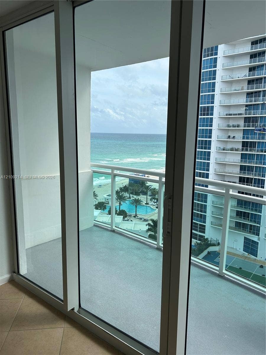 Floor-to-ceiling glass to a private balcony with horizontal railings, featuring direct water and coastal scenery