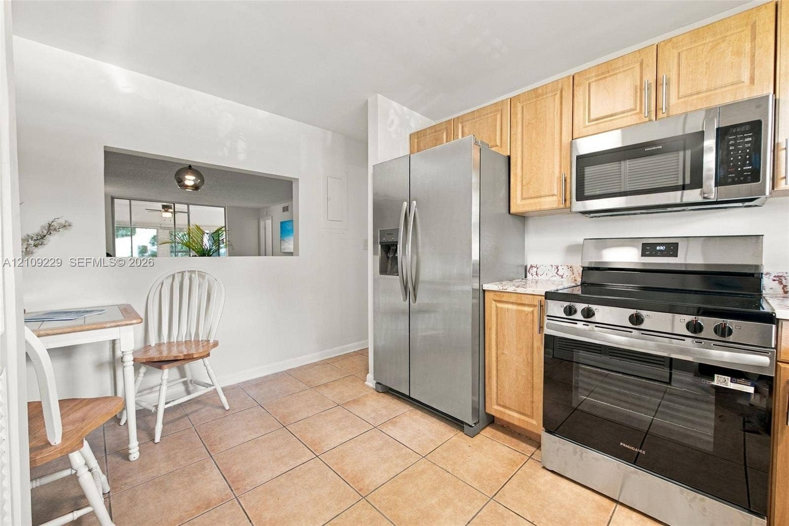 Kitchen featuring light wood cabinetry, stainless steel appliances, and tile flooring