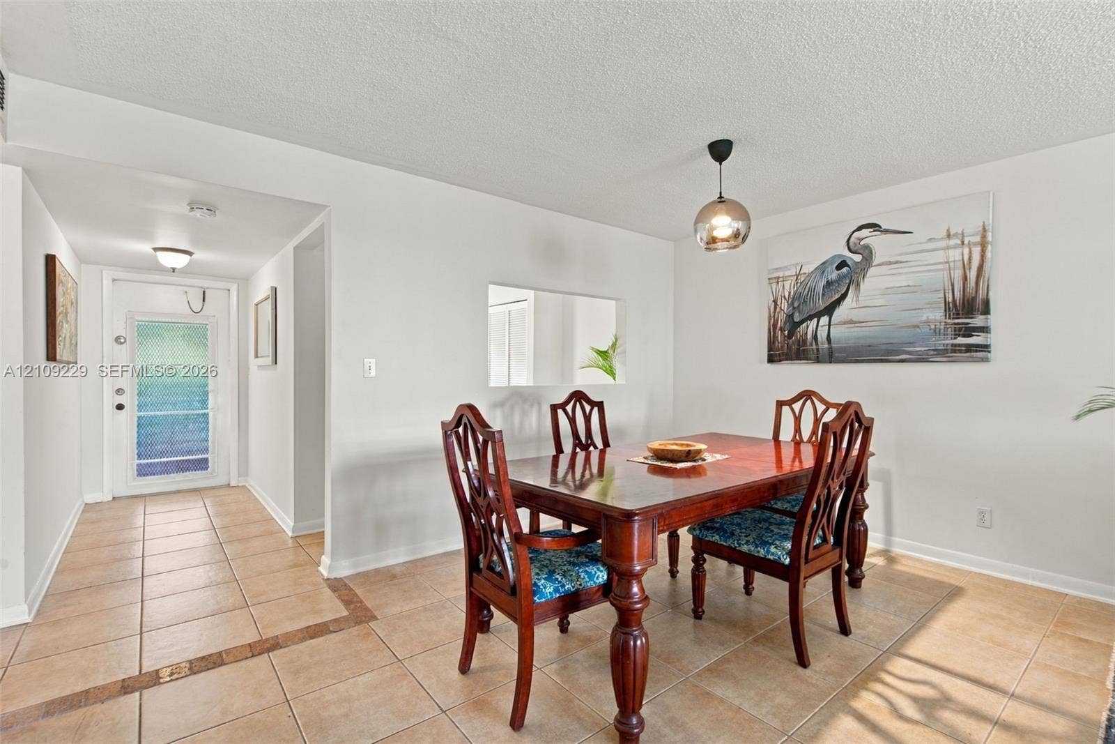 Ceramic tile flooring, decorative glass-paneled entry door, recessed ceiling lighting, and suspended globe pendant fixture