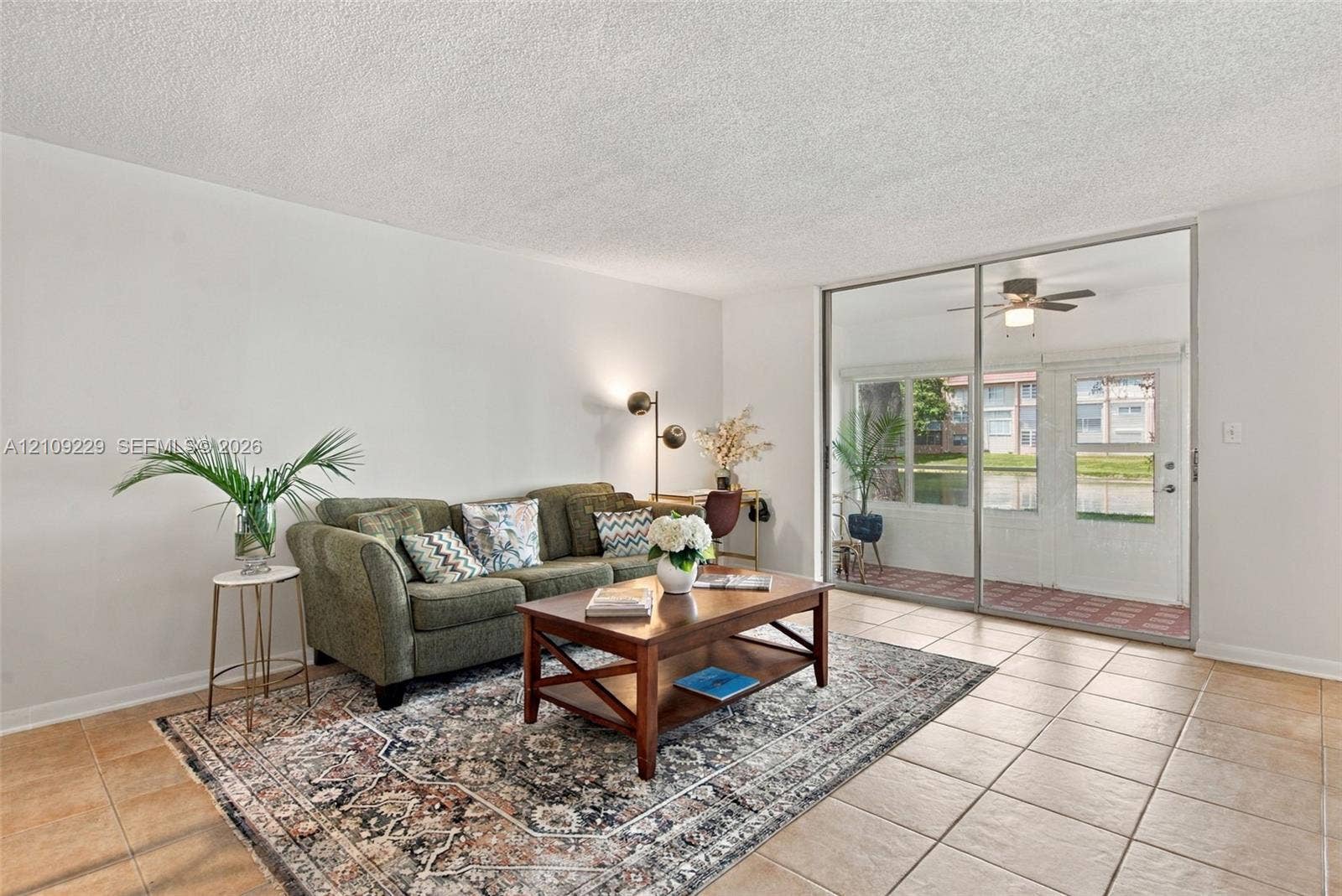 Living area featuring neutral wall paint, tile flooring, and large sliding glass doors providing outdoor access