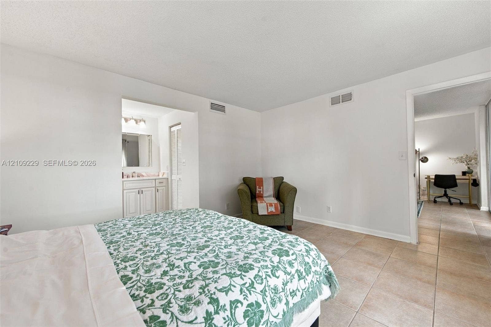 Tile flooring, neutral wall color, and built-in vanity cabinet with mirror and lighting fixture