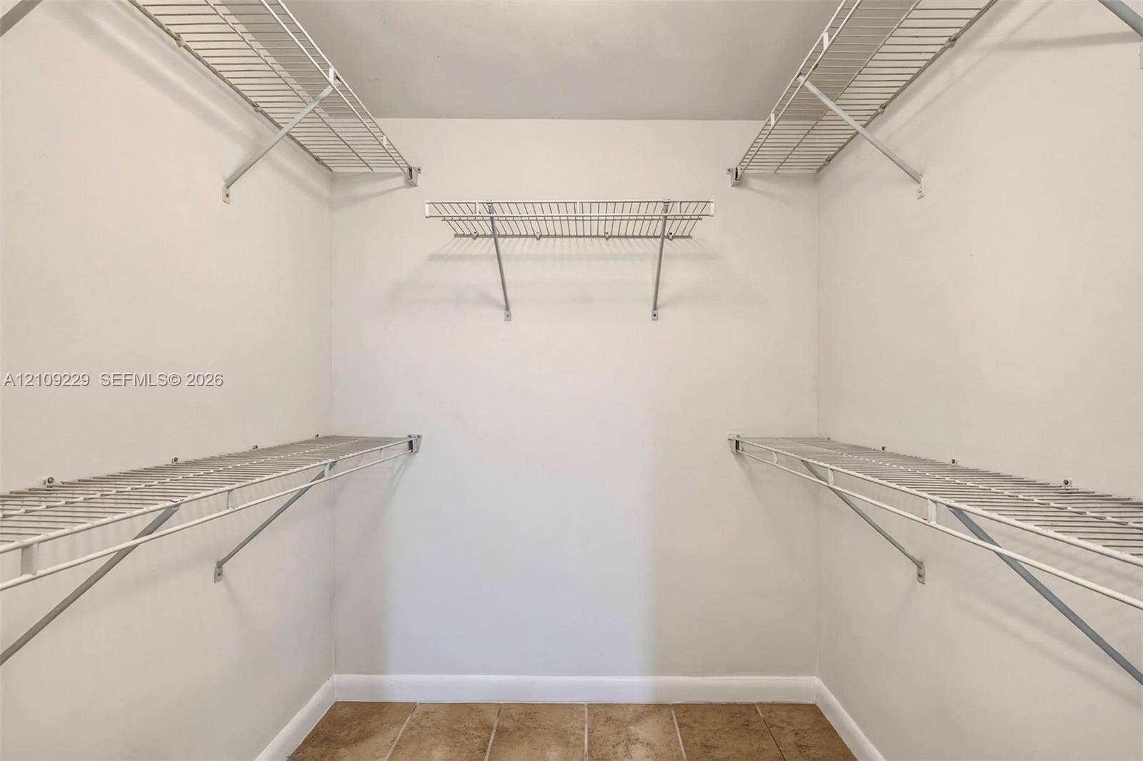 Walk-in closet featuring multi-level white wire shelving and tile flooring
