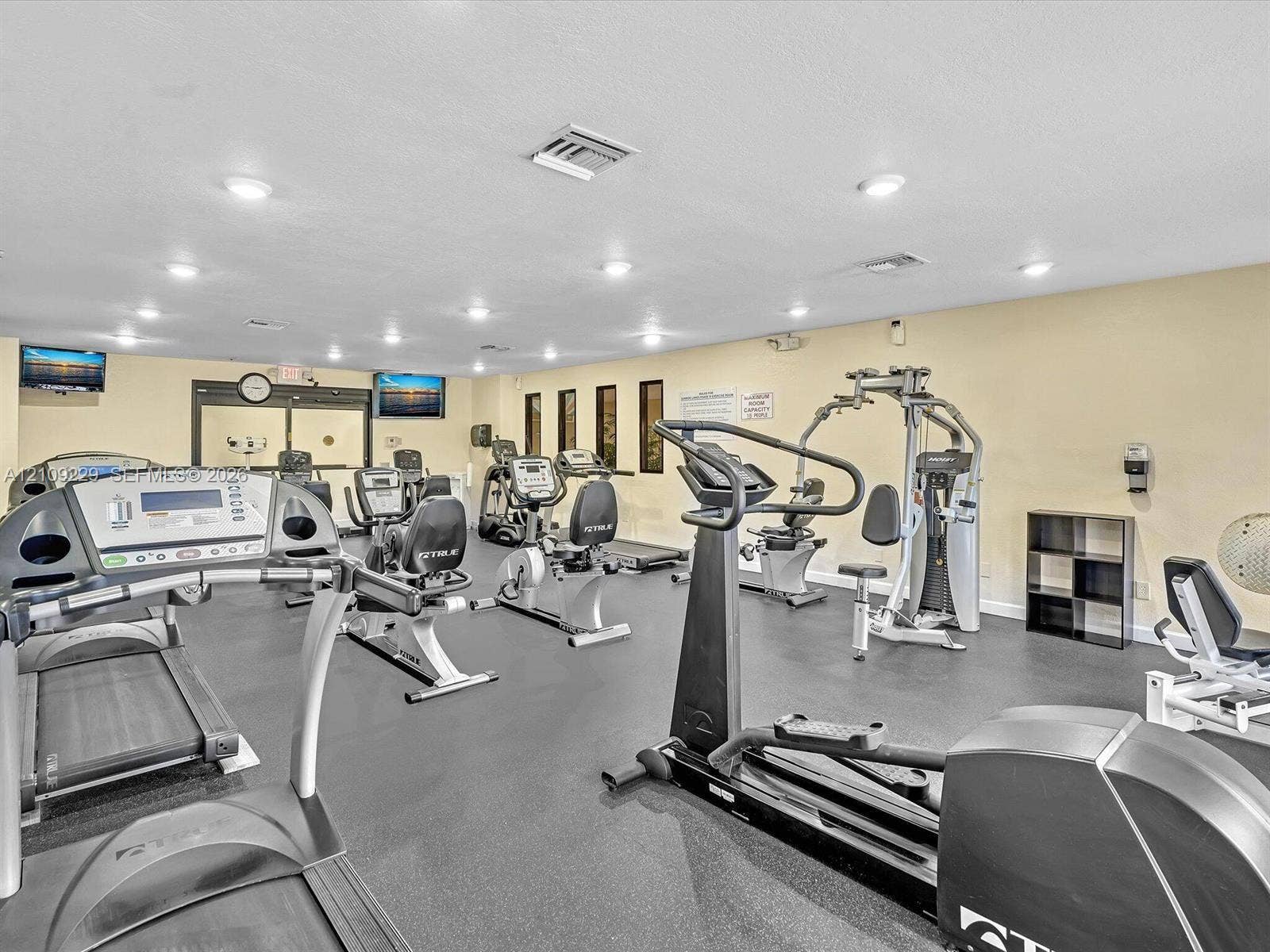 Fitness center featuring rubberized flooring, recessed lighting, and vertical window accents