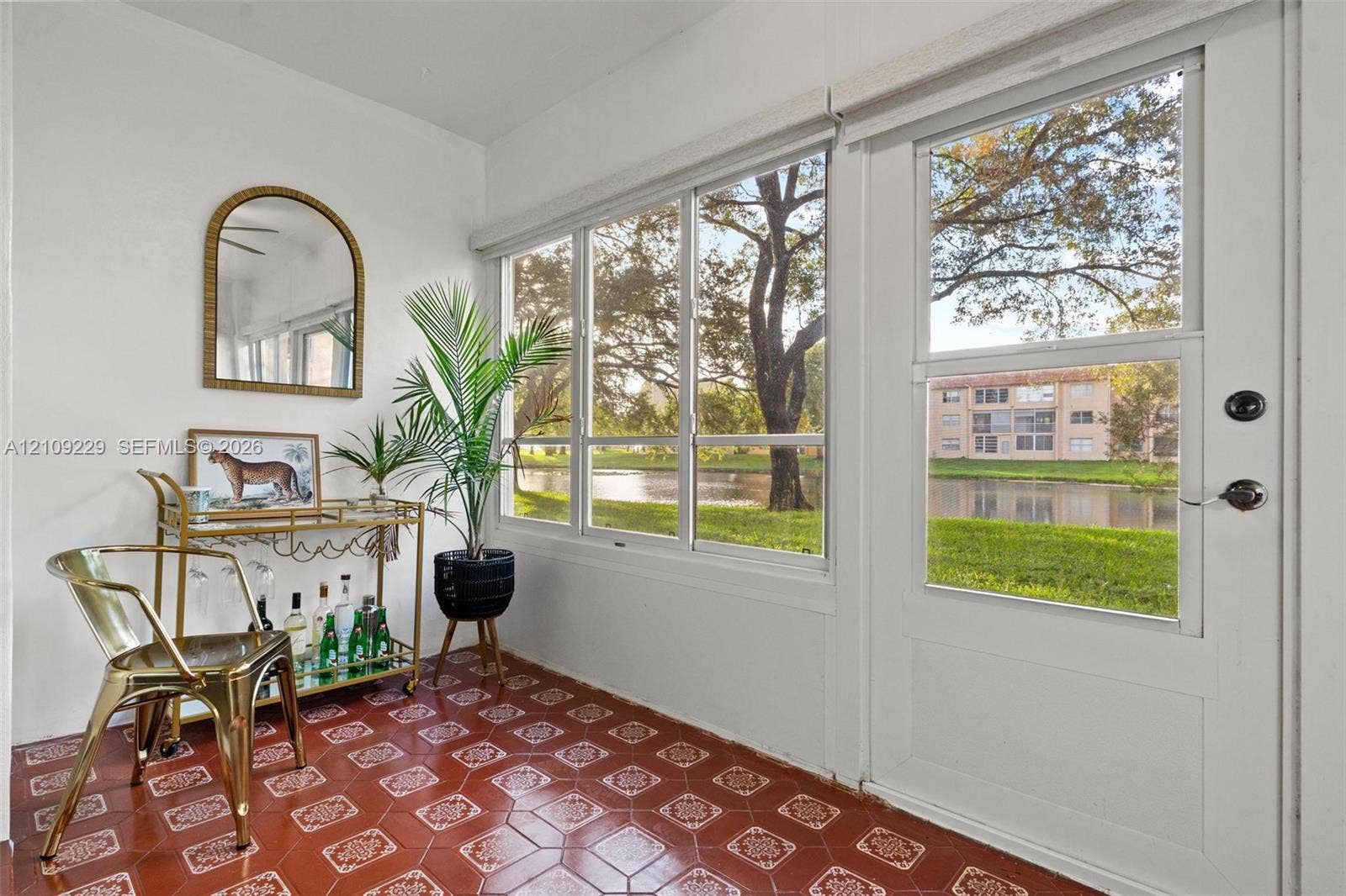 Sunroom featuring patterned terracotta-style tile flooring, floor-to-ceiling windows, and a glass-paneled exterior door