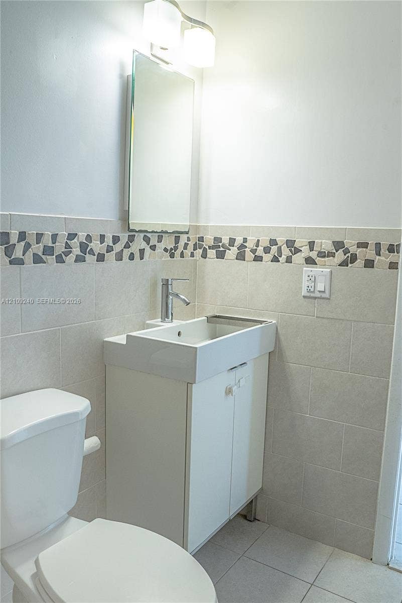 21115 SW 125th Ct Road, Miami, Miami, FL 33177 Wall-mounted vanity featuring a rectangular integrated sink, polished chrome faucet, tiled backsplash with mosaic accent border, and dual-light vanity fixture